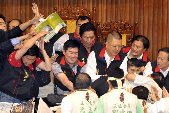 A book is thrown at a group of legislators from Taiwan's ruling Kuomintang party as they try to block their counterparts from occupying a podium at parliament in Taipei on July 8, 2010. (Patrick Lin/AFP/Getty Images)
