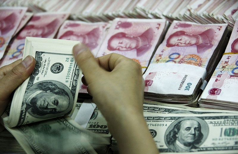 A bank clerk counts a stack of US dollars together with stacks of 100 yuan notes at a bank in Huaibei, China on May 20, 2010. (AFP/AFP/Getty Images) 