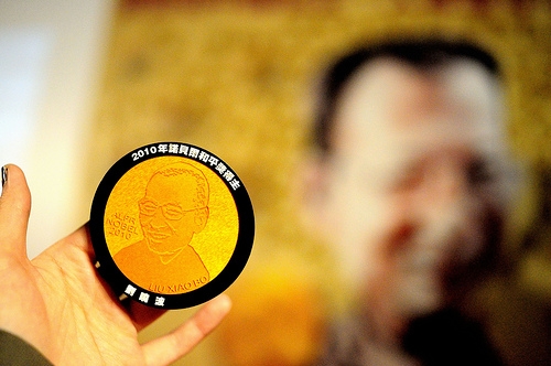 A protester holds a Nobel Peace Prize replica in front of mural depicting jailed dissident Liu Xiaobo in Hong Kong on December 10, 2010. (Flickr user laihiu) 