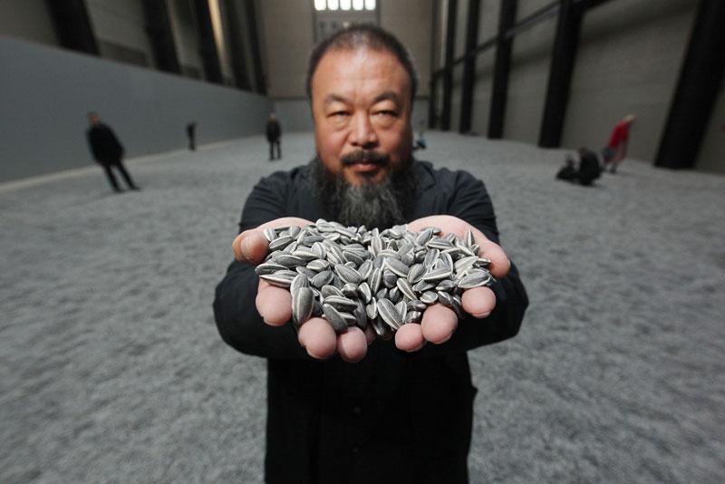 Chinese artist Ai Weiwei holds some porcelain sunflower seeds from his installation at The Tate Modern in London on October 11, 2010. (Peter Macdiarmid/Getty Images)