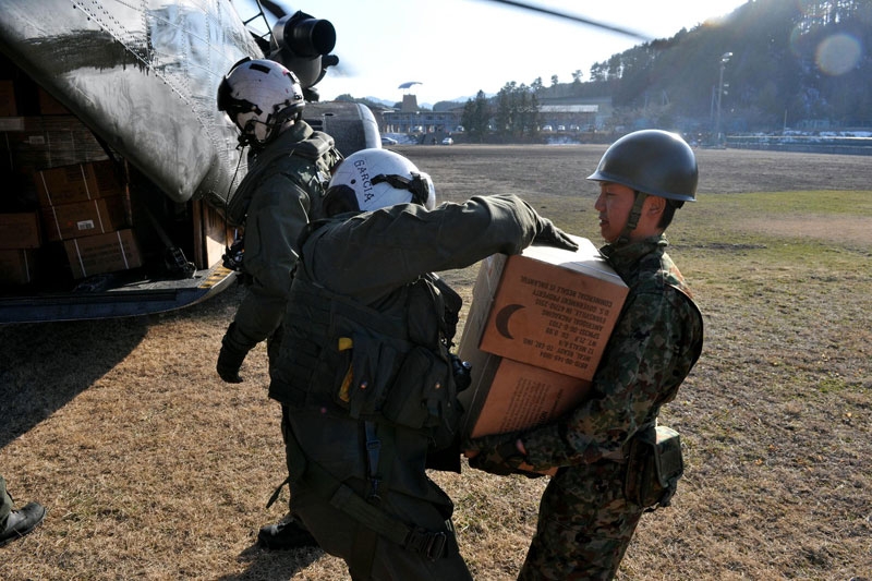 Chief Naval Air Crewman Francisco Garcia (L) delivers meals ready-to-eat to a Japanese Ground Self-Defense Force soldier on Mar. 18, 2011 in Yamada, Japan. (Lt. Eric Quarlesr/US Navy via Getty Images) 