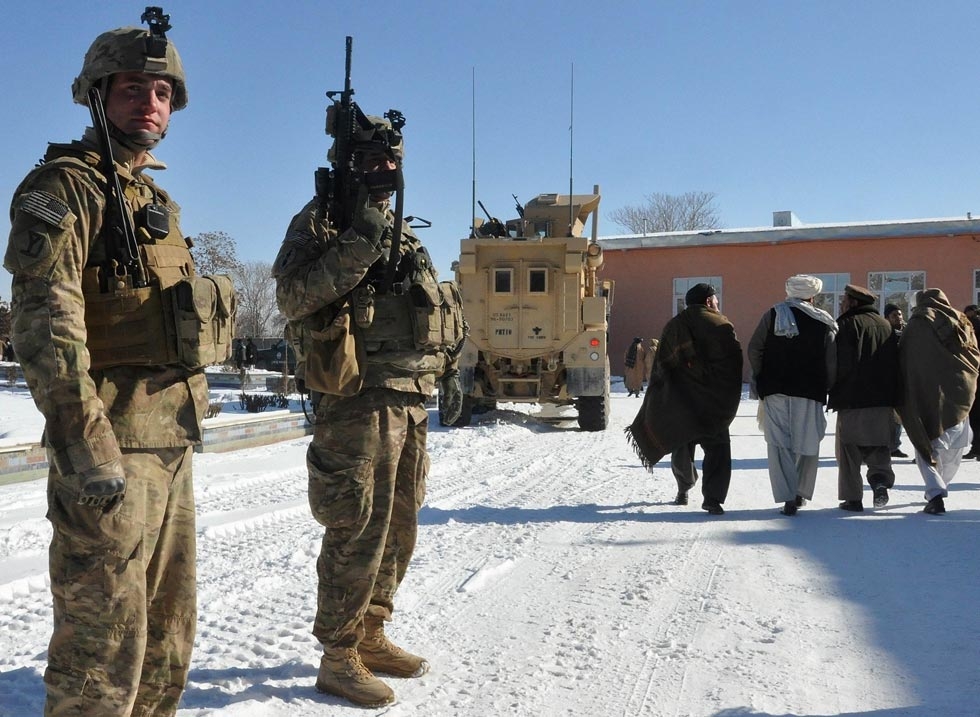 Afghan men walk past by U.S. soldiers in Ghazni province on February 2, 2012. (Aref Yaqubi/AFP/Getty Images)