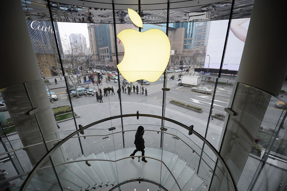 A customer walks under an Apple logo sign at an Apple shop in Shanghai on February 22, 2012. (Peter Parks/AFP/Getty Images)