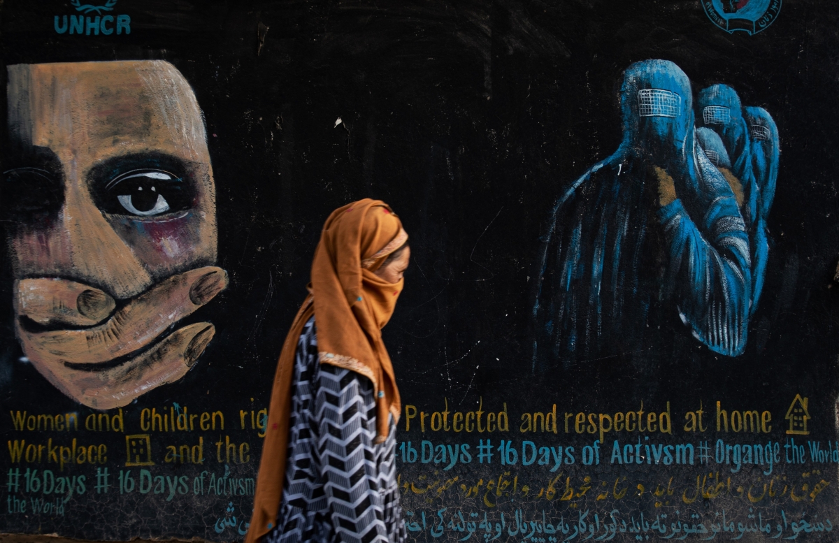 A woman walks past a mural calling for women and children's rights in Afghanistan on August 12, 2022 in Bamian, Afghanistan