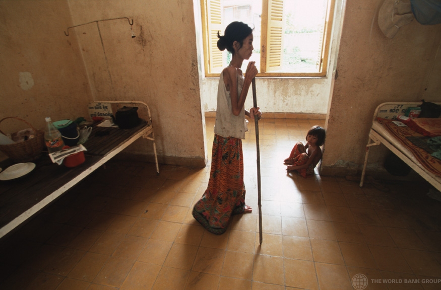 A woman suffering from HIV/AIDS uses a stick to walk back to her bed in hospital. Cambodia. (© Masaru Goto / World Bank) 