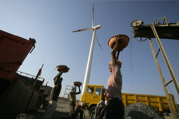 India Bundled Wind: A laborer is seen working at a deisel powered crusher infont of a wind turbine. (Land Rover Our Planet/Flickr)