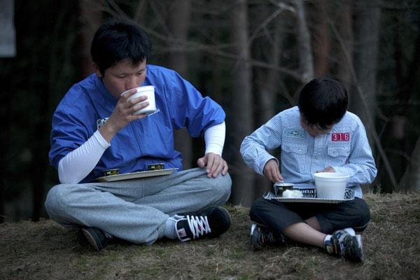 Tsunami survivors Shota Endo (L) and Kei Endo eat relief food outside an evacuation center suffering from power cuts in Shichigahama town, Miyagi prefecture on April 8, 2011. (Yasuyoshi Chiba/AFP/Getty Images) 
