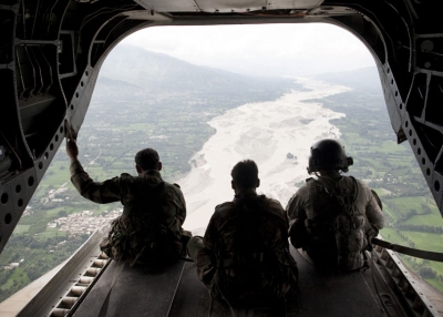 US Army Staff Sargeant Matthew Kingsbury (R) from Bravo Company 2/3 Aviation and Pakistani soldiers sit on the cargo bay ramp of a CH-47 heavy-lift helicopter while looking down at a flooded area while in flight over Swat Valley on August 10, 2010. (Behrouz Mehri/AFP/Getty Images)