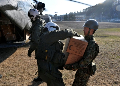 Chief Naval Air Crewman Francisco Garcia (L) delivers meals ready-to-eat to a Japanese Ground Self-Defense Force soldier on Mar. 18, 2011 in Yamada, Japan. (Lt. Eric Quarlesr/US Navy via Getty Images) 