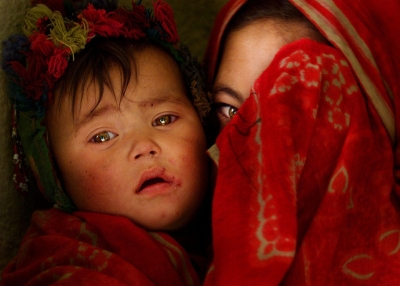 A partially-veiled girl holds a little child close to her side in Afghanistan on June 27, 2012. (james_gordon_losangeles/Flickr)
