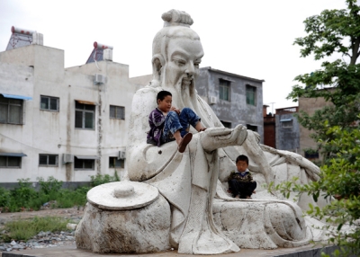 Two children play on a statue outside a factory in Shifosi town, the biggest jade center in the world in Henan, China on May 31, 2013. (Lintao Zhang/Getty Images)