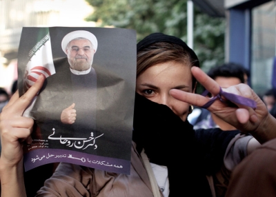 An Iranian woman flashes a victory sign as she holds a portrait of moderate presidential candidate Hassan Rouhani during celebrations in downtown Tehran, June 15, 2013. Iran's Interior Minister has said Rouhani won the election with 18.6 million votes, or 50.68 percent of the vote. (Behrouz Mehr/AFP/Getty Images)