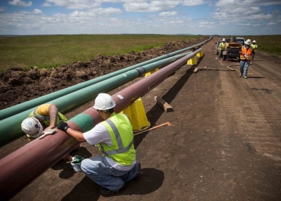 Construction workers specializing in pipe-laying work on a section of pipeline on July 25, 2013 outside Watford City, North Dakota. (Andrew Burton/Getty Images)