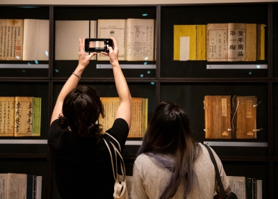 Friends snap a picture of Xiaoze Xie’s “Scrutiny (Premodern Books),” on display as part of Asia Society Museum’s exhibition "Xiaoze Xie: Objects of Evidence."