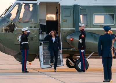 Vice President Harris disembarks helicopter while saluting.