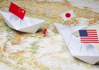 Paper boats with Chinese, Japanese, and American flags are poised over the Diaoyu Islands.