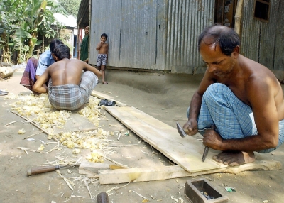 Carpenter Anil Sutradhr, 50, (R) works at his backyard shop, which he opened with a money loan from Grameen Bank microcredit project in Manikganj, Bangladesh.&nbsp;