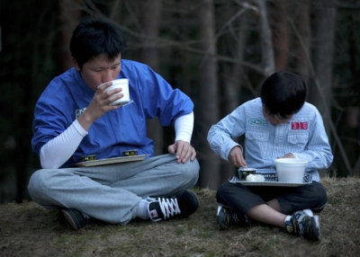 Tsunami survivors Shota Endo (L) and Kei Endo eat relief food outside an evacuation center suffering from power cuts in Shichigahama town, Miyagi prefecture on April 8, 2011. (Yasuyoshi Chiba/AFP/Getty Images) 