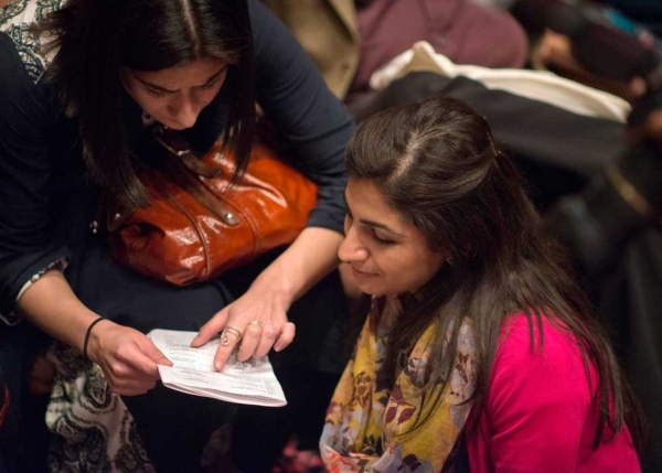 Audience members consulting the LLF program. (Saad Sarfraz Sheikh)