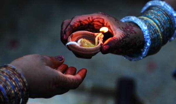An Indian Hindu devotee hand over a traditional oil lamp as they prepare for prayers to the sun during the Chhath Festival while standing in a water body, in Bangalore on November 12, 2010.