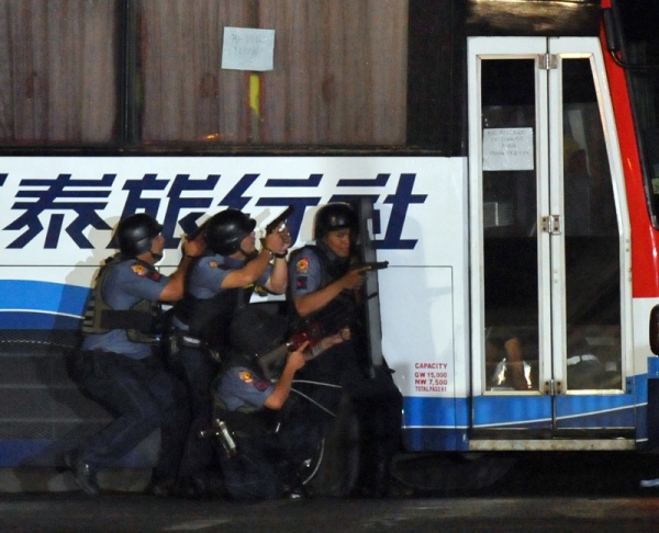 Philippine policemen took cover as they launched their assault on the tourist bus full of Hong Kong tourists hijacked by an ex-policeman in Manila on Aug. 23. Captured live on global television, the chaotic rescue attempt left eight hostages and the gunman dead and prompted widespread outrage across East Asia. (Ted Aljibe/AFP/Getty Images)