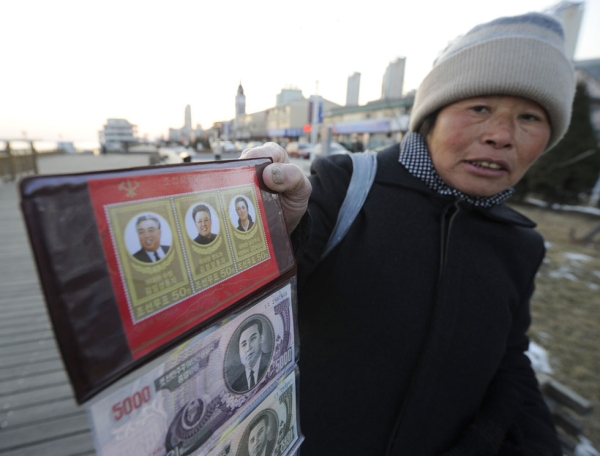 A street peddler shows the North Korean bank notes featuring late North Korean leaders Kim Il Sung and Kim Jong Il along the waterfront of Yalu river in Dandong, in China's northeastern Liaoning province on December 20, 2011. (Liu Jin/AFP/Getty Images)
