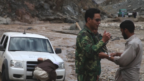 A China Metallurgical Group Corporation employee recruits local Afghans to help move a truck stuck in the mud after heavy rain had caused flooding on the main road. (Brent Huffman)