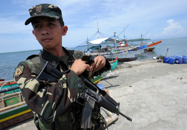 A Philippine soldier stands guard next to fishing boats at a pier in Masinloc town, Zambales province, 140 miles from Scarborough Shoal on May 18, 2012. Philippine President Benigno Aquino told protesters to abort plans to sail May 18, to the disputed South China Sea shoal also claimed by China. (Ted Aljibe/AFP/GettyImages)