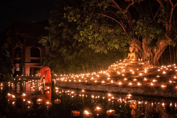 A monk lighting candles in a pond during Visakha Bucha, a day that celebrates Buddha's birth, enlightenment and death, in Chiang Mai, Thailand on June 4, 2012. (CanvasOfLight/Flickr)