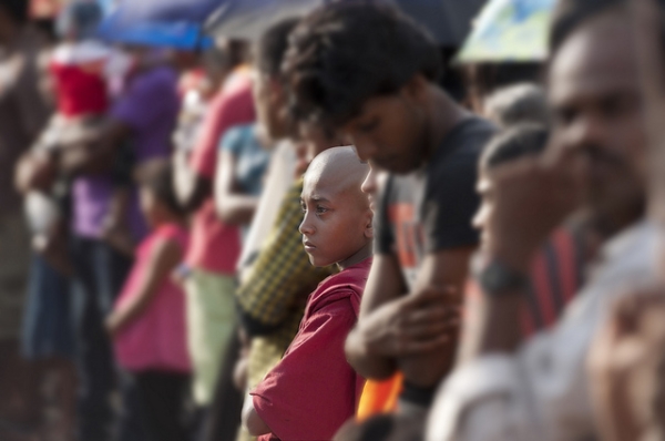 A young monk watches a street parade amidst a full crowd in Hikkaduwa, Sri Lanka on May 5, 2012. (Brett Davies/Flickr)