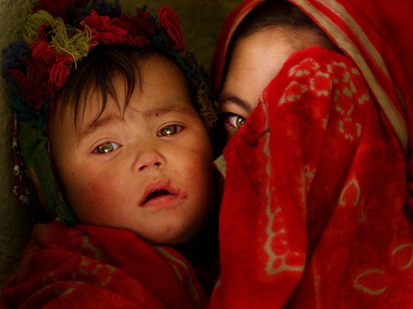 A partially-veiled girl holds a little child close to her side in Afghanistan on June 27, 2012. (james_gordon_losangeles/Flickr)