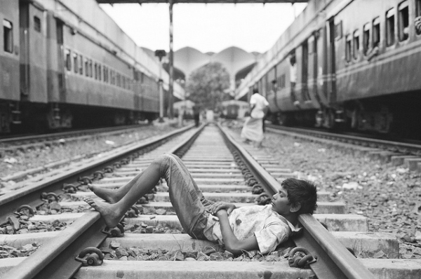 A young boy takes a nap on the rails in Dhaka, Bangladesh on September 21, 2012. (BatulTheGreat/Flickr)  