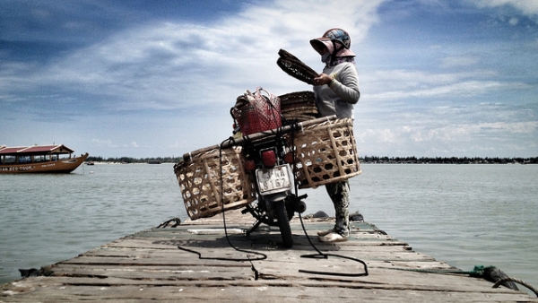 A motorcycle owner parked by the serene waters of Hoi An in Vietnam on September 2, 2012. (Simon Marussi/Flickr)
