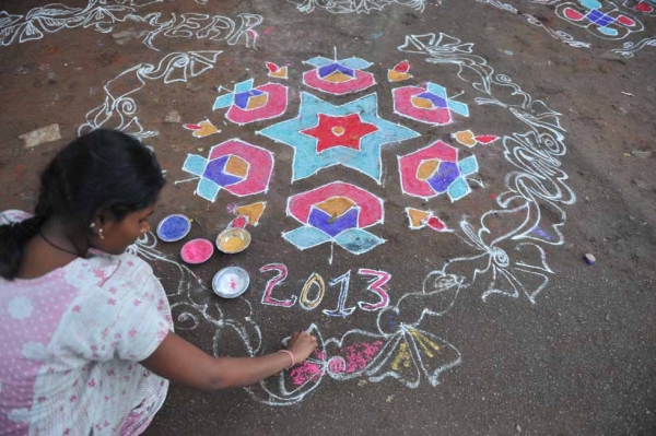 A woman applies colored powder to her "rangoli," a Hindu ritual design, in front of her house in Hyderabad, India on January 1, 2013. (Noah Seelam/AFP/Getty Images)