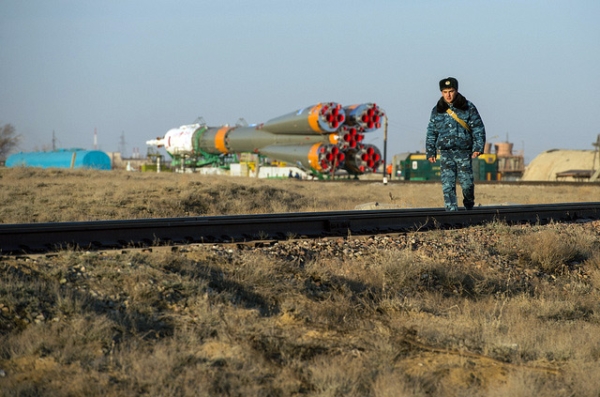 A Russian security guard is seen walking along the train tracks with the Soyuz rocket in the background at the Baikonur Cosmodrome in Kazakhstan on March 26, 2013. (nasa hq photo/Flickr)