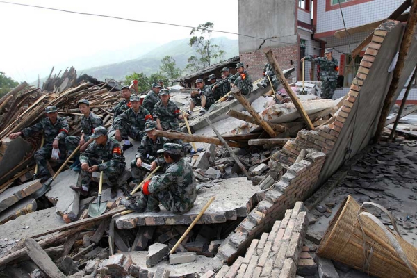 Rescuers sit on ruins of a house in Longmen township, close to the epicenter of a magnitude 7.0 earthquake that hit the city of Ya'an, southwest China's Sichuan province on April 20, 2013. (STR/AFP/Getty Images)