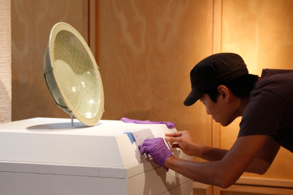 Hiroaki Sato places a description on the stand for a porcelain platter. (Tahiat Mahboob/Asia Society)