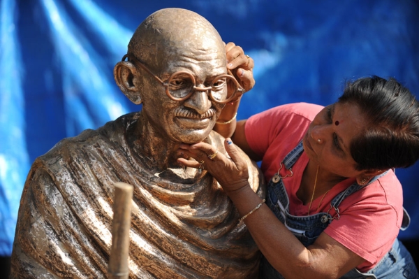Indian artist Jasuben Shilpi, known as the Bronze Woman of India, adjusts the glasses on a bronze statue of Mahatma Gandhi at her workshop near Ahmedabad, India on December 23, 2011. (Sam Panthaky/AFP/Getty Images)