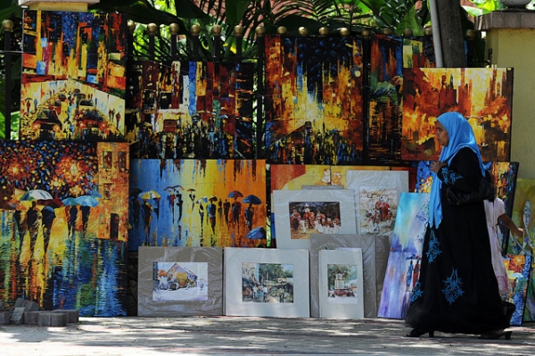 A woman walks past colorful paintings for sale on the roadside in Colombo, Sri Lanka on September 28, 2013. (Lakruwan Wanniarachchi/Getty Images)