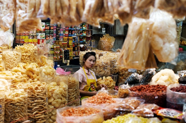 A shopkeeper is surrounded by her dried goods and wares at an indoor market in Bangkok, Thailand on January 1, 2014. (Tord Sollie/ Flickr)