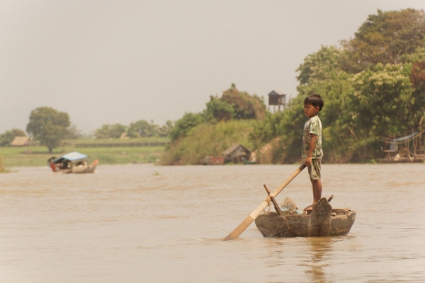 A young boy drifts on a boat all alone in Kampong Chhang, Cambodia on February 24, 2014. (Suivez-Nous . Asia/Flickr)