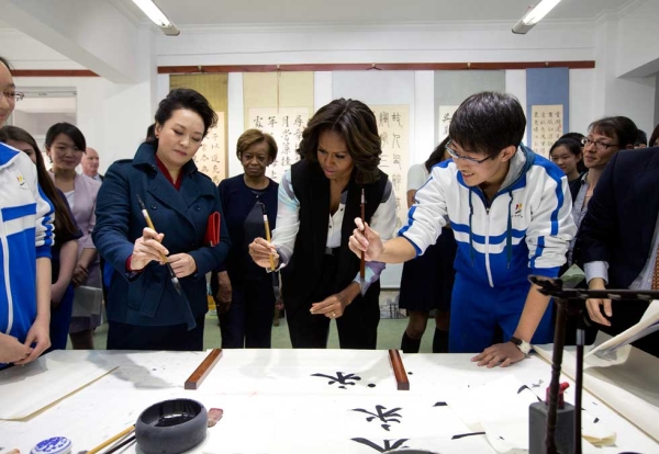Peng Liyuan, wife of Chinese President Xi Jinping (L), shows U.S. First Lady Michelle Obama (C) how to wield a writing brush as they visit a traditional calligraphy class at the Beijing Normal School on March 21, 2014. (Andy Wong-Pool/Getty Images) 