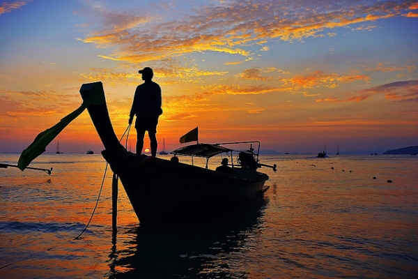 A fisherman stands alone on a boat during sunrise in Trang, Thailand on May 1, 2014. (Roberto Trm/Flickr)