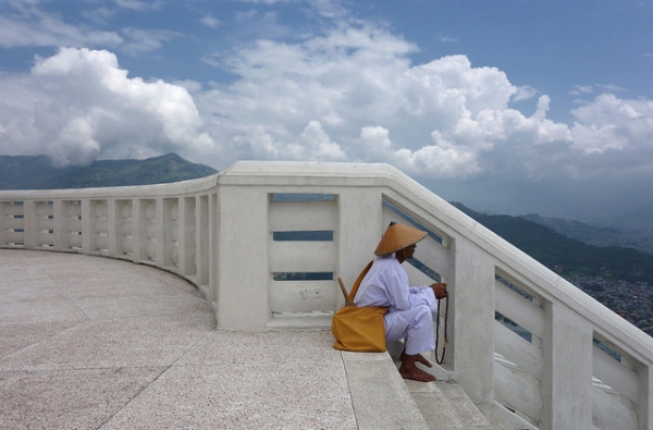 A man counts prayer beads at the top of World Peace Monument Pokhara in Nepal on July 8, 2014. (drburtoni/Flickr)