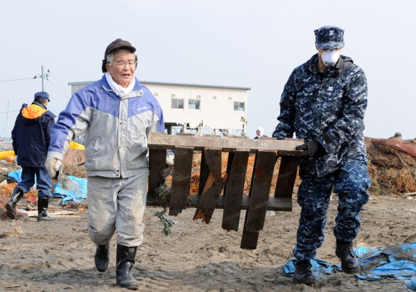 John Dicola (R) of the U.S. Navy assists in removing debris during a cleanup effort at the Misawa Fishing Port in Japan on March 14, 2011. Photo by Devon Dow. (Flickr/U.S. Pacific Fleet)