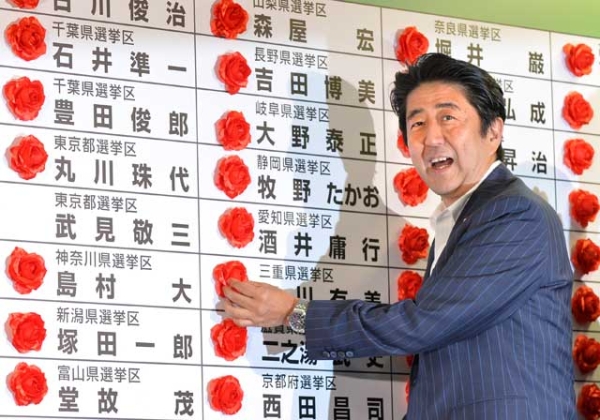 Japan's Prime Minister and President of the Liberal Democratic Party (LDP) Shinzo Abe smiles as he places a red paper rose on an LDP candidate's name to indicate an election victory at the party's headquarters in Tokyo on July 21, 2013. (Kazuhiro Nogi/AFP/Getty Images) 