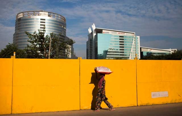 A pedestrian walks past a construction site near corporate offices in Gurgaon, on the outskirts of New Delhi, India on October 5, 2013. (Andrew Caballero-Reynolds/AFP/Getty Images)
