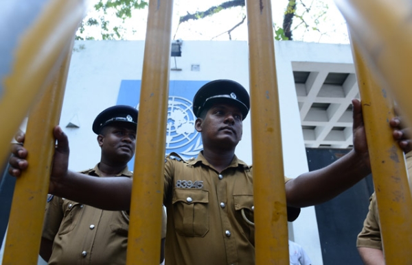 Sri Lankan policemen look on as Tamil pro-government activists take part in a demonstration outside the UN offices in Colombo on March 10, 2014, to protest a proposed US-led UN resolution to investigate Sri Lanka for alleged war crimes. (Lakruwan Wanniarachchi/AFP/Getty Images)