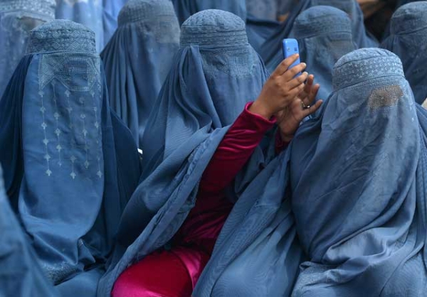 An Afghan woman takes a photograph with her mobile phone at an election rally in Jalalabad on February 18, 2014. Smartphone technology, writes Ahmad Shuja, played a vital role in ensuring a free and fair election for Afghanistan in April 2014. (Shah Marai/AFP/Getty Images)