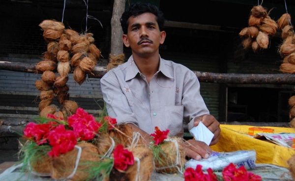 A vendor sells flowers and coconuts outside a temple in Mumbai. (Angeline Thangaperakasam and Michael Newbill/Asia Society India Centre)